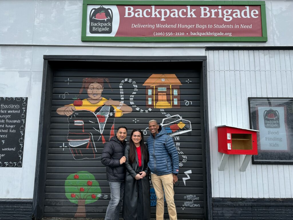 Remitly employees in front of the Backpack Brigade sign